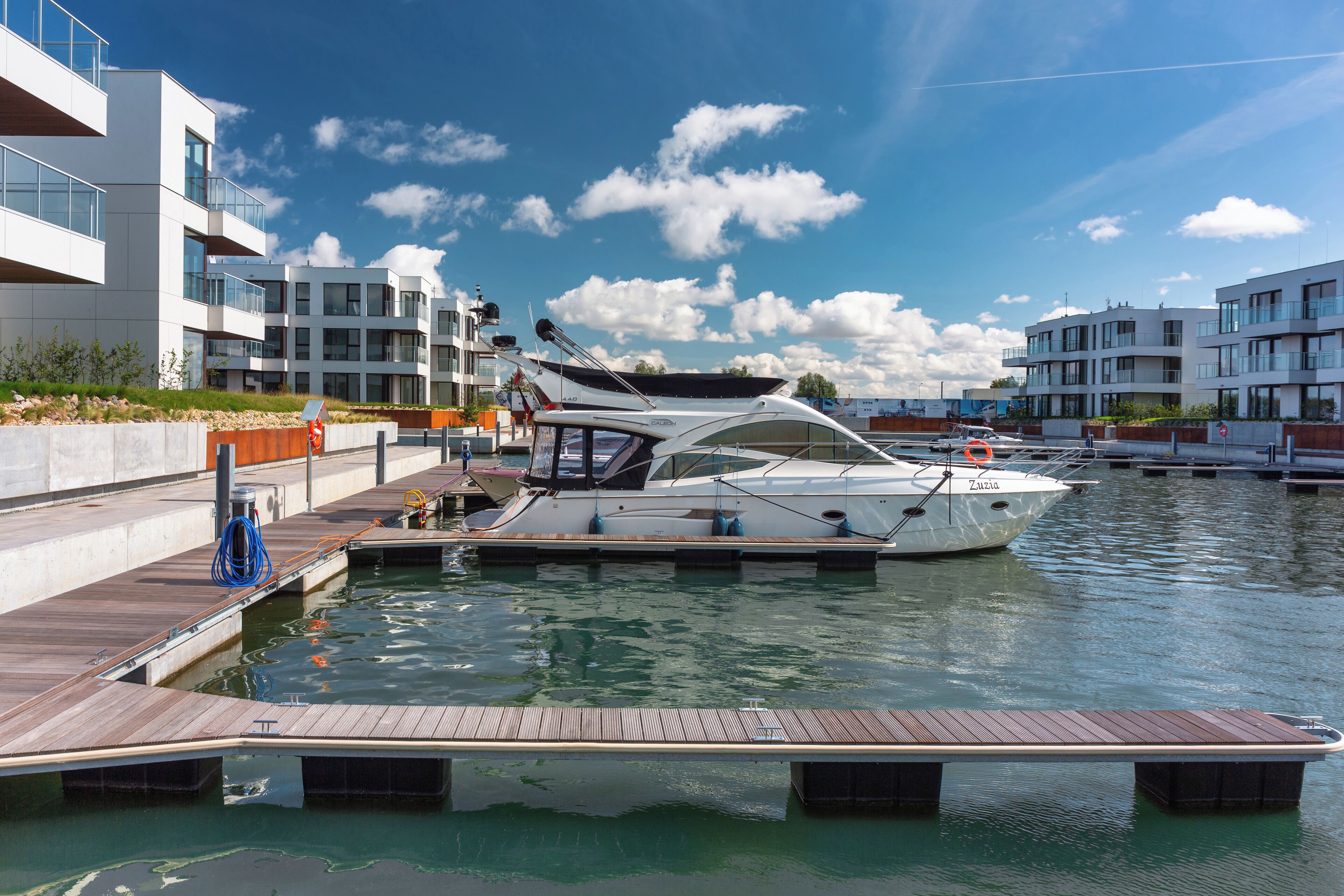 A marina with modern buildings, a dock, and a boat.