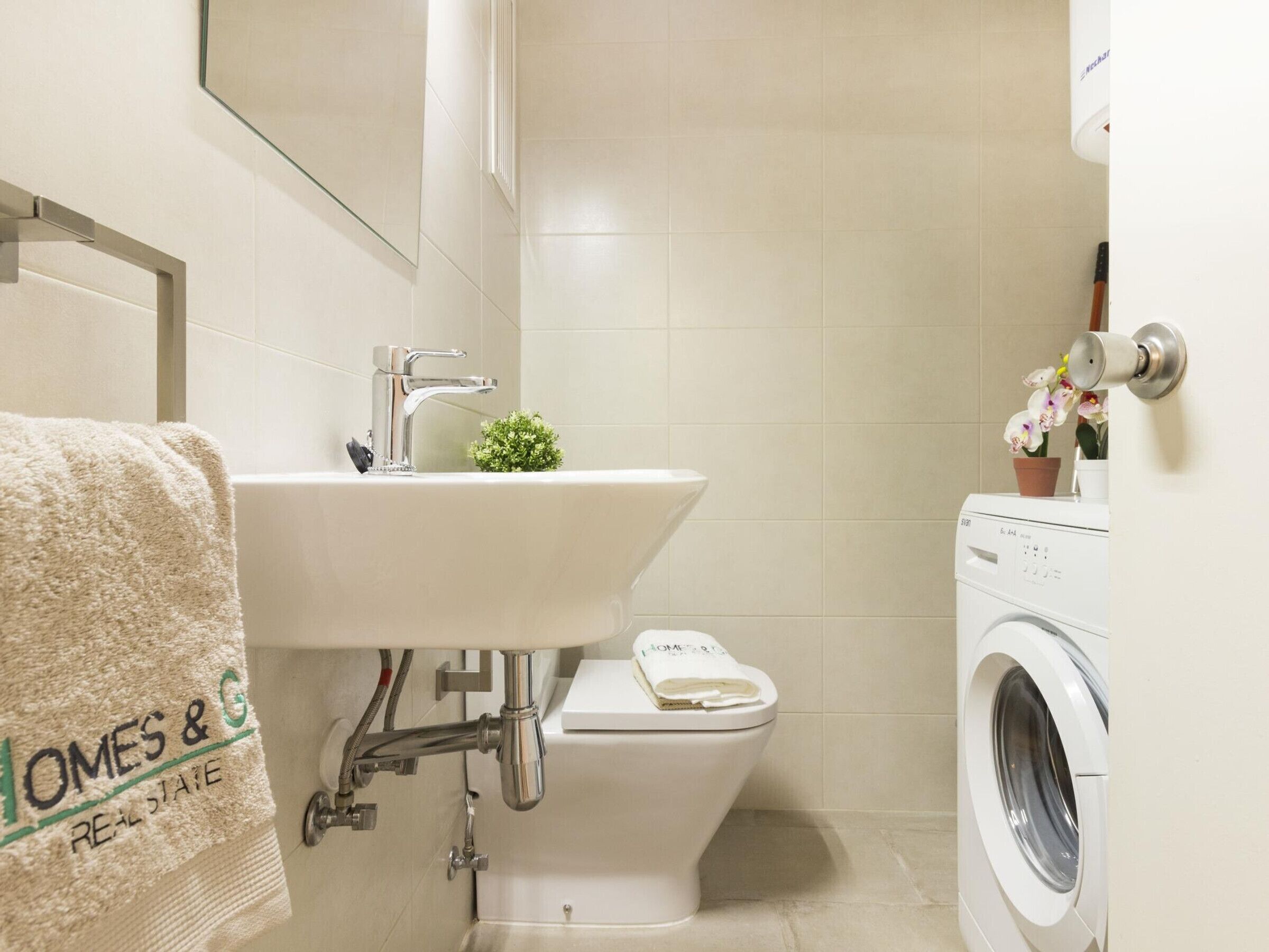 A bathroom with a sink, toilet, and washing machine.
