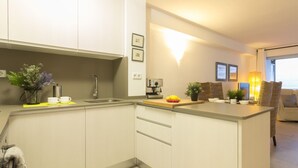 Eine moderne Küche mit Kochinsel, einer Kaffeemaschine und einem Spülbecken. Auf der Arbeitsfläche stehen Blumentöpfe und eine Vase.