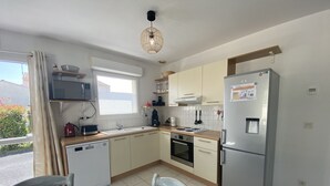 Una cocina compacta equipada con lavavajillas, estufa, refrigerador y un comedor con mesa y sillas.