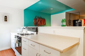 A kitchen with white cabinets, a teal accent wall, and a countertop.