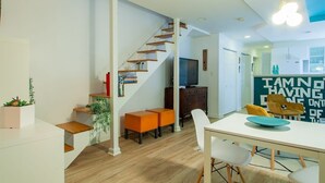 A modern living space with a staircase, a dining area, and a kitchen.