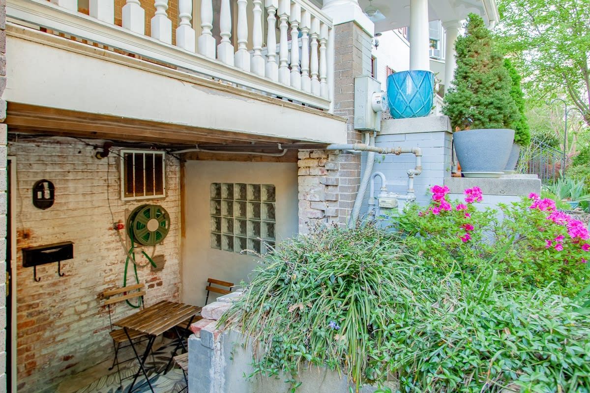 A rustic building with a brick facade, a wooden bench, and a potted plant.