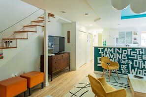 A modern kitchen with a built-in refrigerator, wooden cabinets, and a dining area with a table and chairs.