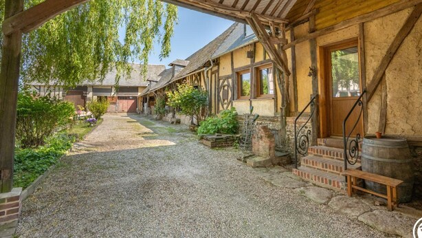 Ein rustikaler Innenhof mit Kiesweg, Holzbanken und einem Fass.