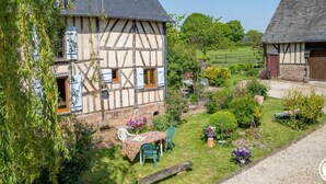 Ein traditionelles Fachwerkhäuschen mit Garten, einem Tisch mit Stühlen und einem kleinen Teich.