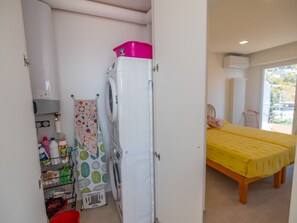 A laundry area with a washing machine, a drying rack, and a small storage shelf with cleaning supplies. - Stunning 2BR Top-Floor Apt with A/C, Sea View Terrace, Near Beach & Center (Menton)