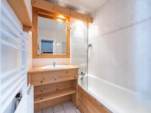 Une salle de bain avec un meuble-lavabo en bois, un évier, un miroir et une douche à parois de verre.