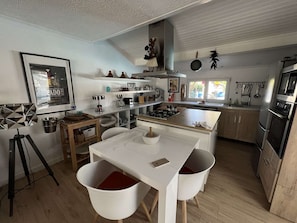 A modern kitchen with a central island, wooden cabinets, and stainless steel appliances.