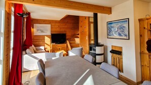 Ein gemütliches Holzhaus mit Essbereich, Kamin und Fernseher.