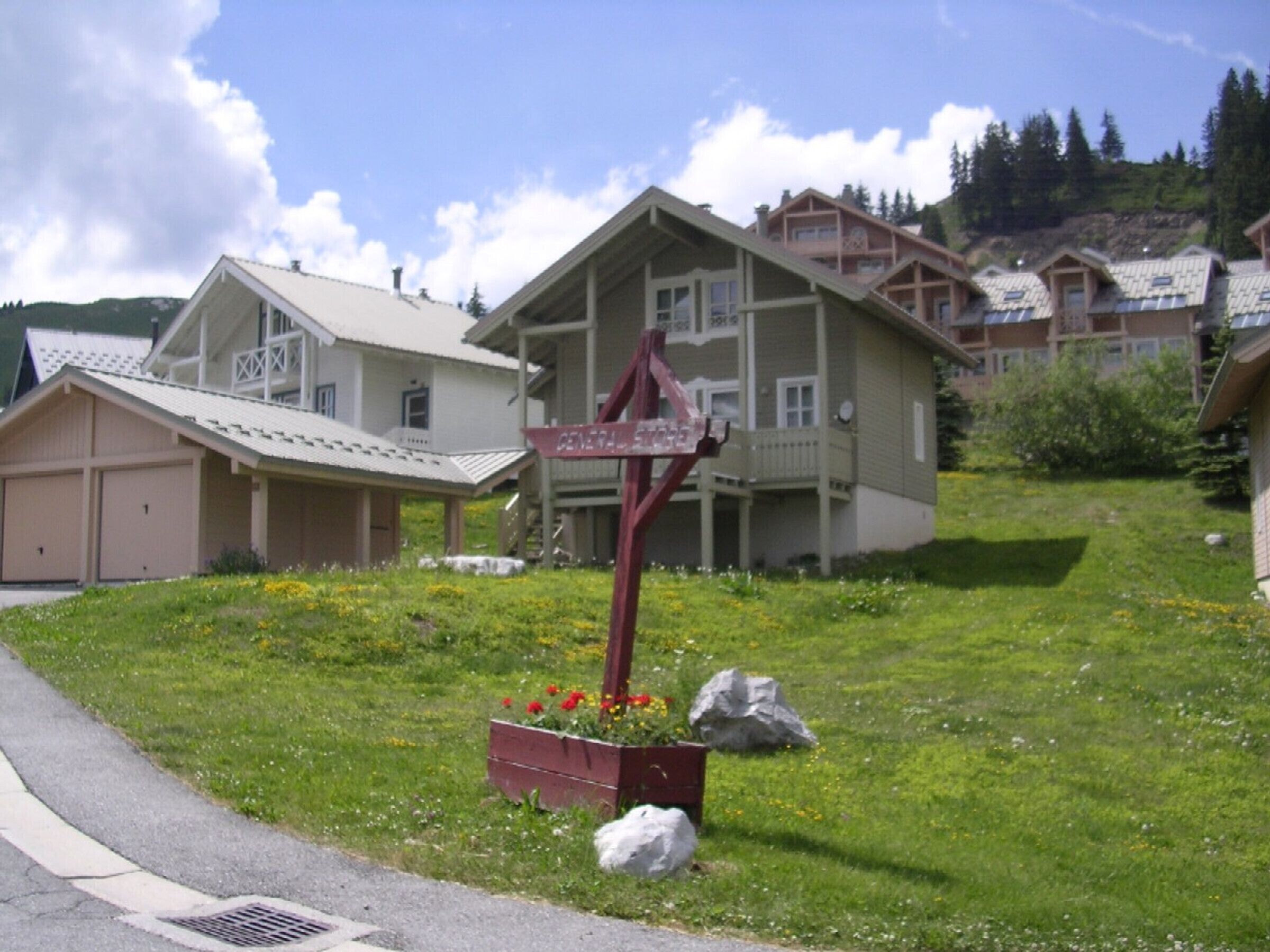A residential area with houses, a signpost, and a flower bed.