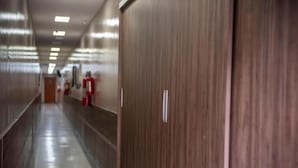 Un long couloir étroit, avec des portes en bois d’un côté et un extincteur visible sur le mur.