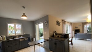 A modern kitchen with dark cabinets, a dining table, and a large window. - Spacious Villa in Fouras, 10 mins from Beach, Sleeps 6, Modern Comforts, WiFi, Large Garden (Fouras)