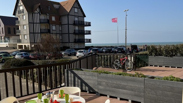 Una terraza con mobiliario exterior, una bicicleta y vistas al mar y edificios.