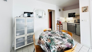 A compact living space with a dining area, kitchenette, and a mirrored wall. - 4-person apartment with sea view, beachfront (Fouras)