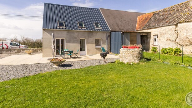 A modern house with a sloped roof, a patio with outdoor furniture, and a stone wall. - Cozy House near Utah Beach, Pets Allowed (Carentan les Marais-Vierville)