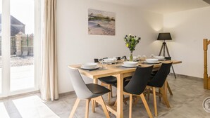 A dining area with a table set for four, a vase with flowers, and a painting on the wall. - Cozy House near Utah Beach, Pets Allowed (Carentan les Marais-Vierville)