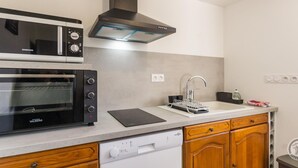A compact kitchen with a built-in microwave, oven, and dishwasher. - Cozy House near Utah Beach, Pets Allowed (Carentan les Marais-Vierville)