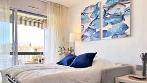 A hotel room with a bed, a nightstand, a lamp, and a wall with artwork.