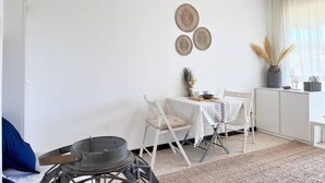 A minimalist living space with a dining area, a small kitchen, and a view of the outdoors.