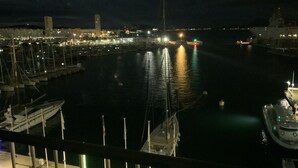 Een jachthaven bij nacht met aangemeerde boten, een stadsachtergrond en helder water.
