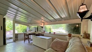 A cozy room with a sofa, a dining table, and a window overlooking greenery. - Charming house with enclosed garden in Saint-Pierre-des-Loges (Saint-Pierre-des-Loges)