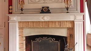 A fireplace with a decorative mantel, a clock, and a candelabra. - Charming house with enclosed garden in Saint-Pierre-des-Loges (Saint-Pierre-des-Loges)