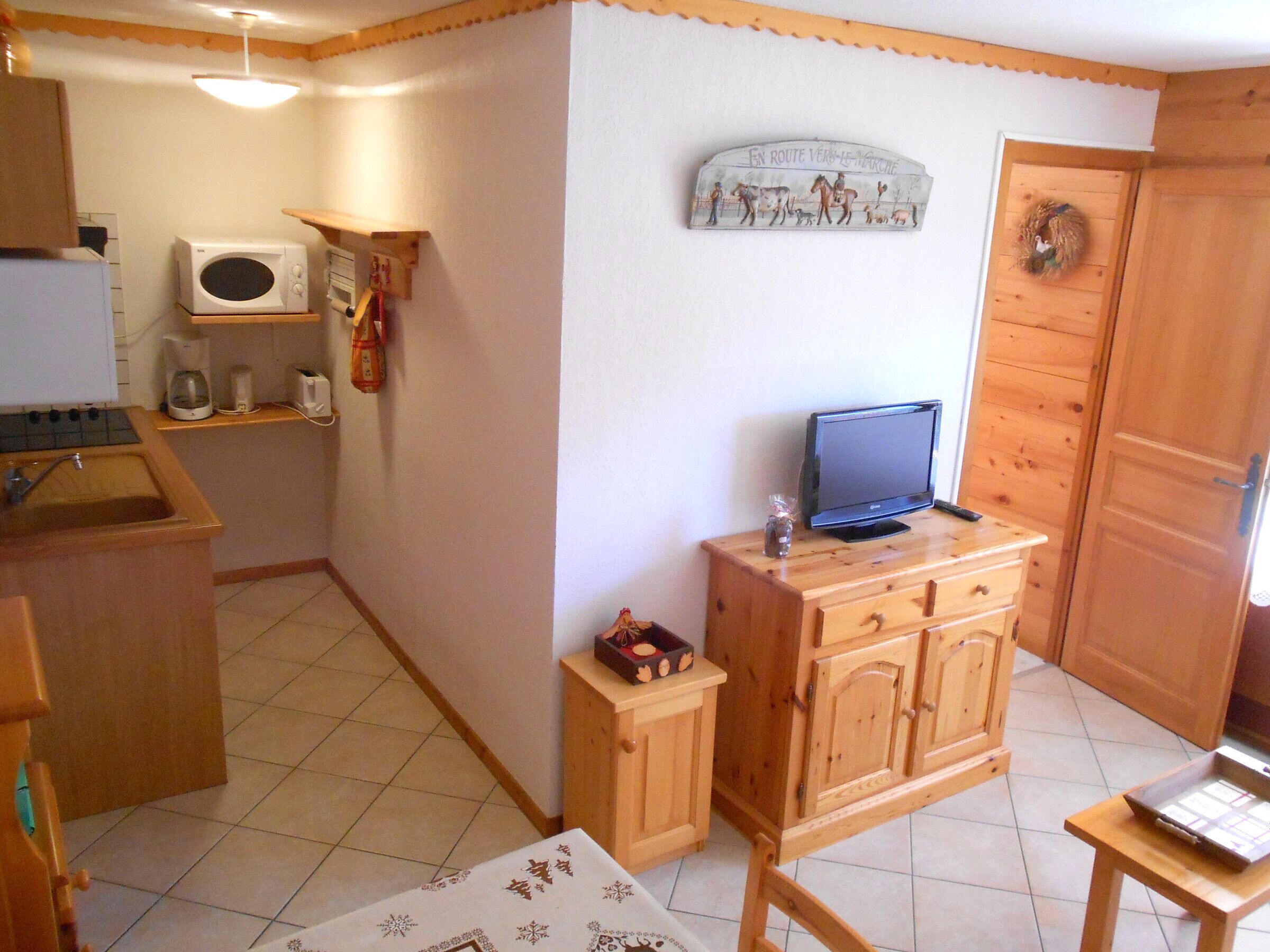 A small kitchen with a microwave, coffee maker, and wooden cabinets.