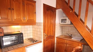 A compact kitchen with wooden cabinets, a built-in microwave, a toaster oven, and a small sink. - Studio mezzanine Les Saisies - 4 pers, south balcony, station center (Les Saisies)
