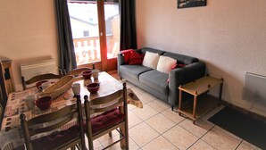 A cozy living room with a grey sofa, a dining table with chairs, and a wooden ceiling. - Studio mezzanine Les Saisies - 4 pers, south balcony, station center (Les Saisies)