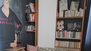 Un coin lecture confortable avec un canapé vert, une petite table en bois et une bibliothèque remplie de livres.