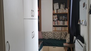 Une petite pièce comprenant un lit superposé, une bibliothèque et un radiateur.