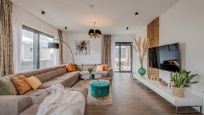 A modern living room with a sectional sofa, a round coffee table, and a TV mounted on the wall.