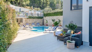 A modern outdoor pool area with lounge chairs and a seating area.