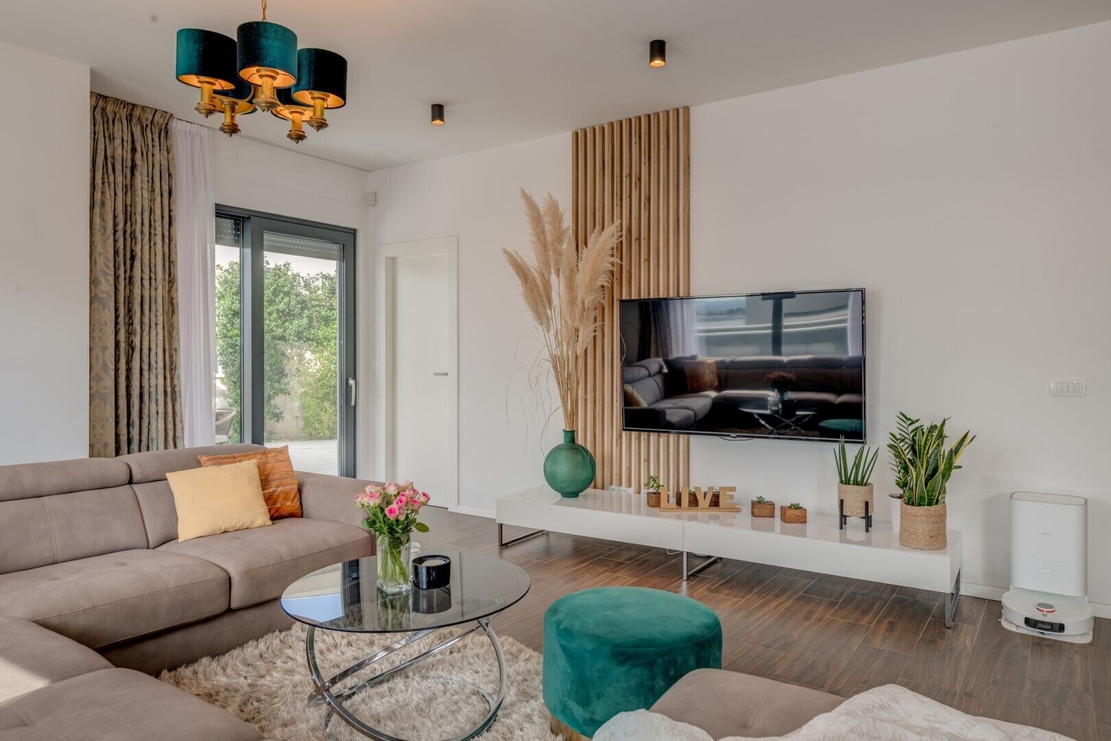 Ein modernes Wohnzimmer mit einer Couch, einem Glastisch, einem Fernseher und Zimmerpflanzen.