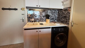 Cozinha compacta com máquina de lavar, pia e bancada com suporte para facas.
