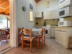 A compact kitchen with a washing machine, microwave, and wooden chairs around a table. - Townhouse in La Palmyre, 5 people (La Palmyre)