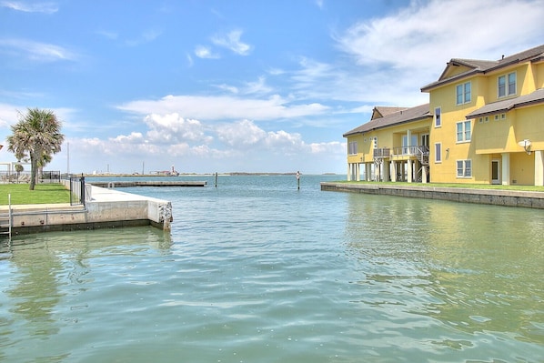 A waterfront property with a dock, a yellow building with balconies, and a clear view of the water.