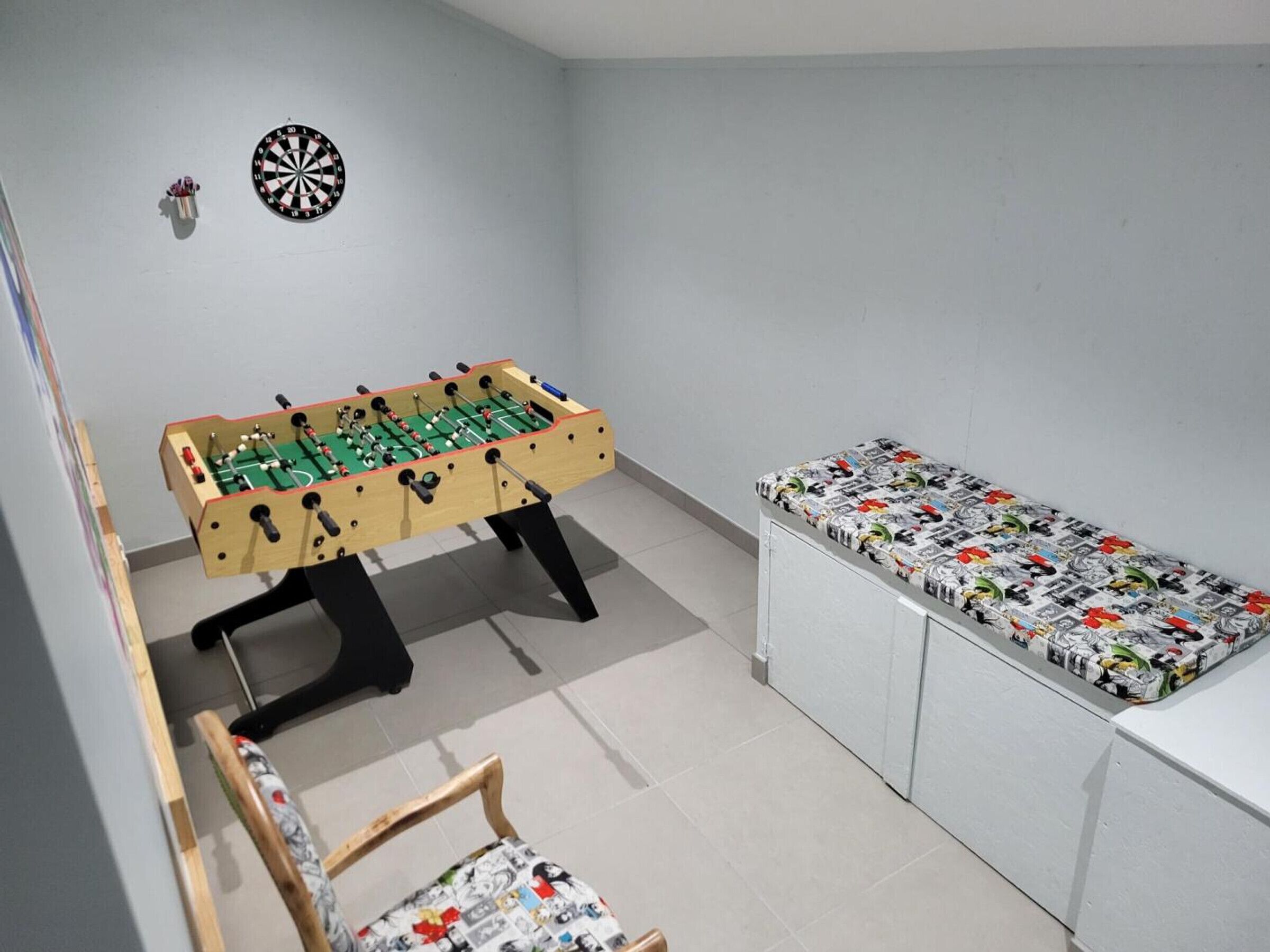 Una habitación con mesa de fútbol de mesa, dardo y banco con diseño.