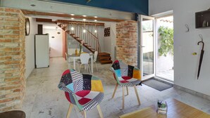 A modern interior with exposed brick walls, a staircase, and a dining area with a white table and chairs. - Comfortable cottage with private garden in Balbigny (Balbigny)