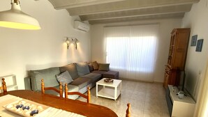 Uma sala de estar com uma mesa de jantar de madeira, um sofá e um rack para televisão.
