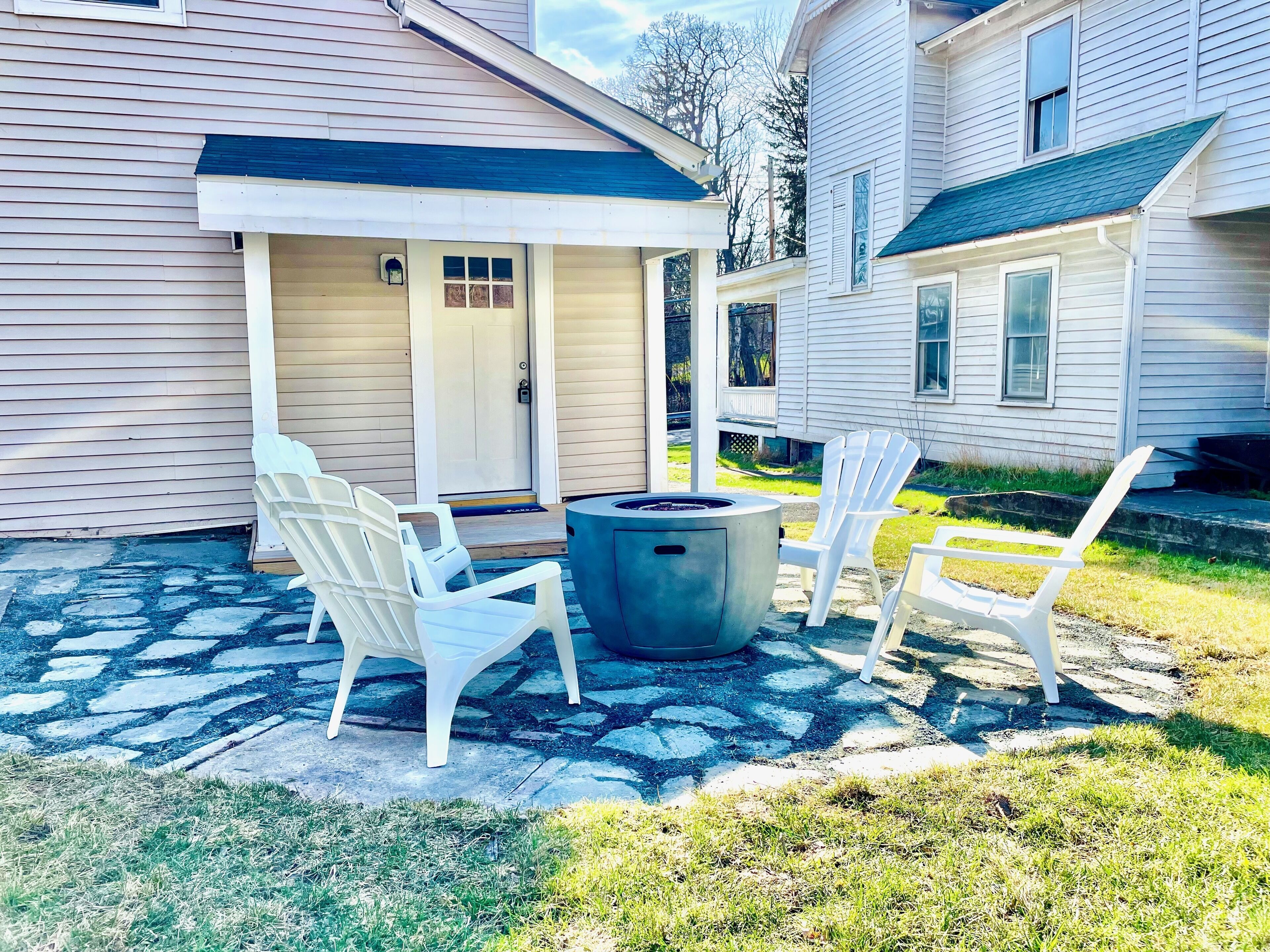 Un patio con sillas Adirondack y un brasero.