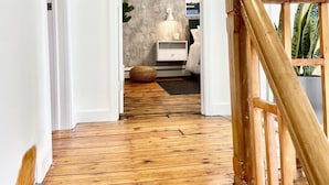 A wooden staircase leading to a bedroom with a bed, bedside table, lamp, and a wall with a textured pattern.