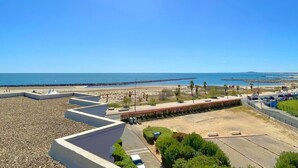 A coastal view with a beach, a parking area, and a clear sky. - Stunning T3 with sea view terrace, parking (Sète)