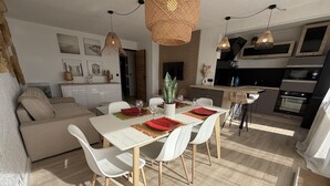A modern kitchen with a dining area, white furniture, and a large window. - Stunning T3 with sea view terrace, parking (Sète)