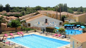 A large rectangular swimming pool with multiple lanes, surrounded by lounge chairs and umbrellas. - Cozy Studio with Pool Access, A/C, and Terrace in Port Ambonne (Cap d'Agde naturisme)