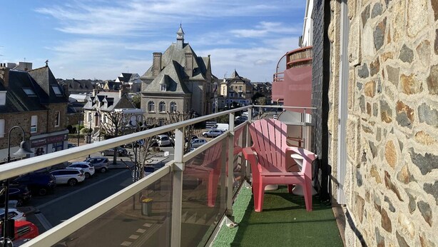 A balcony with a stone wall and a view of a town with historic buildings.