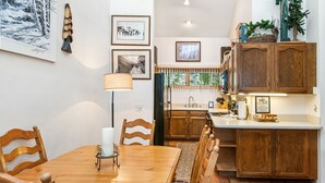 A dining area with a wooden table and chairs, a candle centerpiece, and a rug.