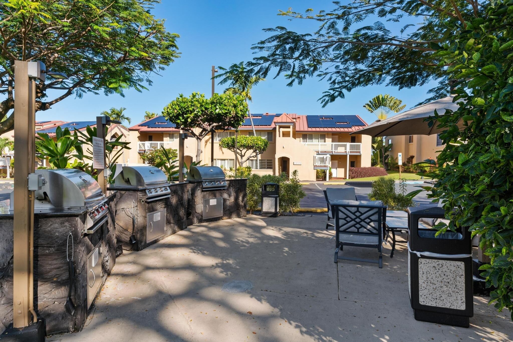 Un espace extérieur aménagé en terrasse, avec des barbecues, des sièges et une vue sur les immeubles d’habitation en arrière-plan.