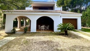Ein modernes Haus mit Ziegeldach, einer überdachten Terrasse mit Sitzgelegenheiten und einer Garage.